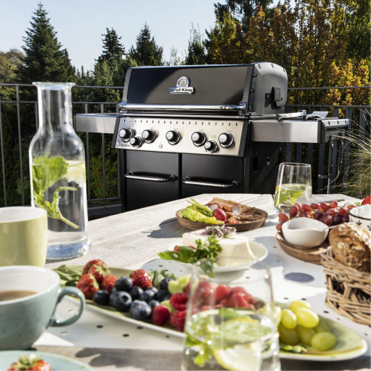 Broil King Baron 590 876283 Gas Barbecue, in a garden with food