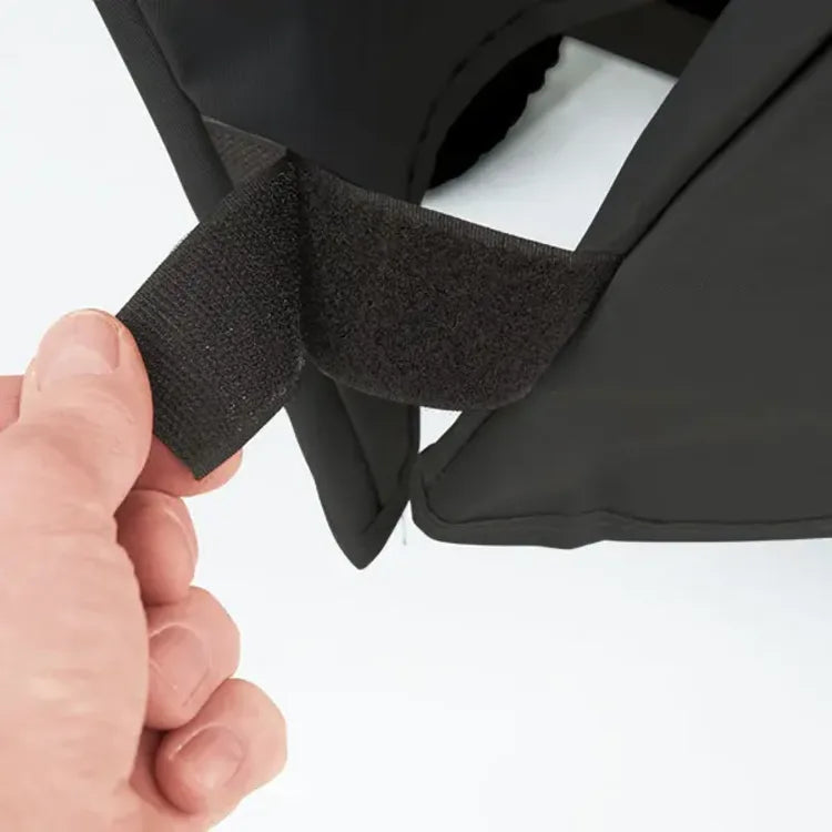 Broil King Select 67470 Grill Cover in Black, hand pulling a hook-and-loop strap at the hem