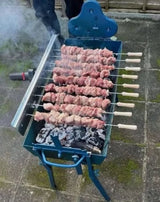 Cyprus BBQ charcoal rotisserie (foukou) grill in use, souvlaki skewers turning over charcoal