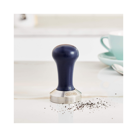 De'Longhi DLSC058 Coffee Tamper, on a counter with ground coffee