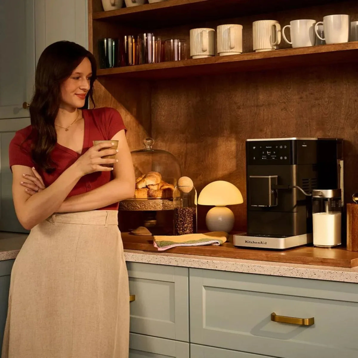 KitchenAid 5KES8454 in Matte Black, on a kitchen worktop beside a woman holding a cup