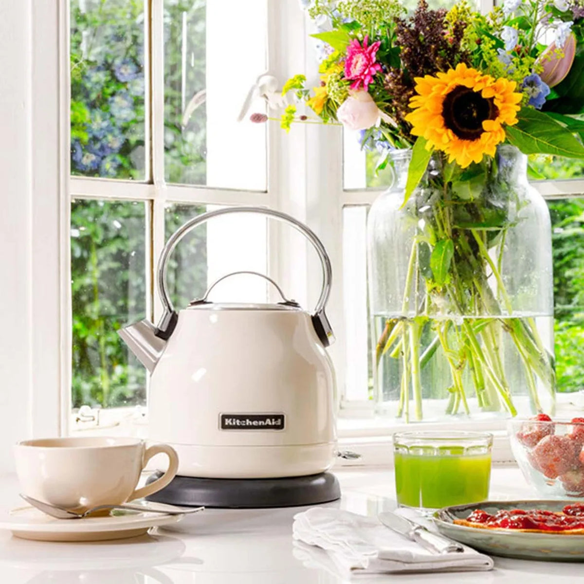 KitchenAid 5KEK1222BAC, on a sunny windowsill beside flowers, a cup and breakfast