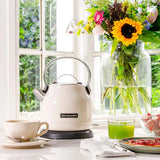KitchenAid 5KEK1222BAC, on a sunny windowsill beside flowers, a cup and breakfast