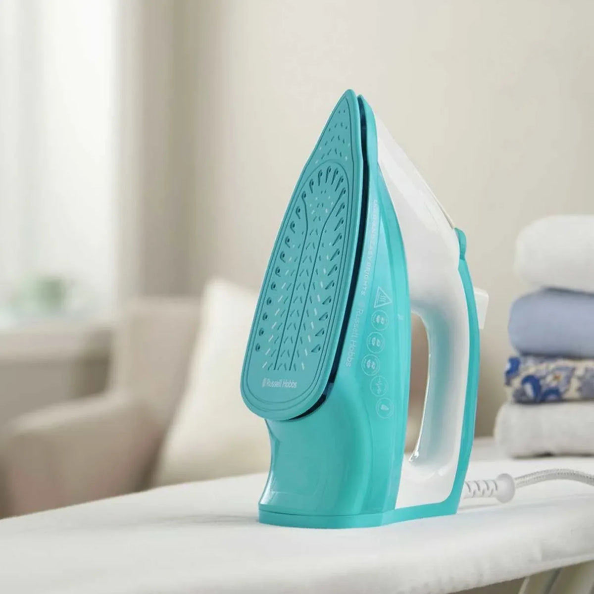 Russell Hobbs 26470, standing upright on an ironing board beside folded towels