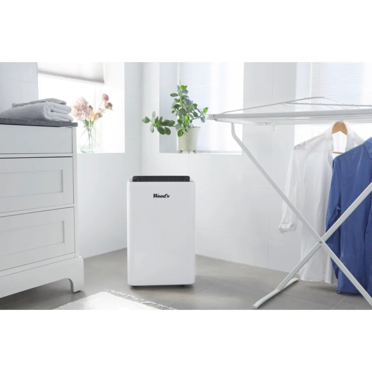 Wood's MRD20GW in White, standing near a clothes airer with hanging shirts